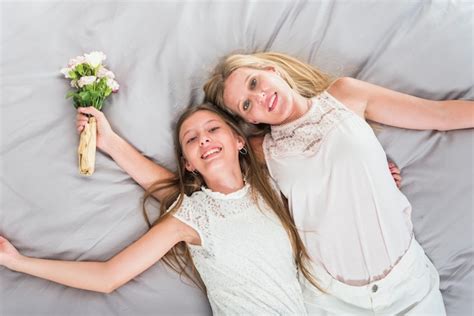 Free Photo Happy Mother And Daughter Lying On Bed With Flowers