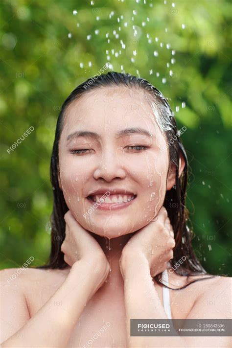 Attractive Smiling Young Asian Woman With Closed Eyes Taking Shower On