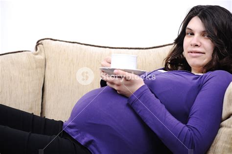 Beautiful Pregnant Woman Sitting On The Couch And Drinking Coffee