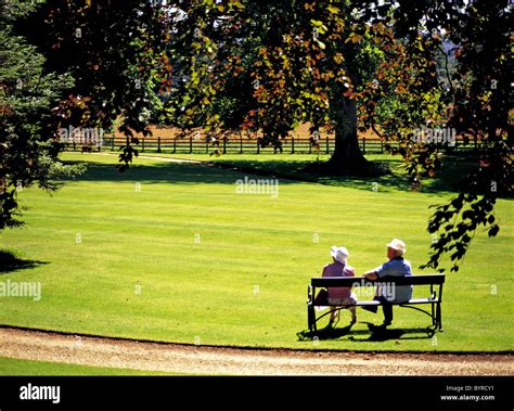 Elderly Couple Seated On Park Bench Surrey England Stock Photo Alamy