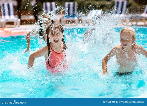 Children Laughing While Splashing Water In Swimming Pool Stock Image