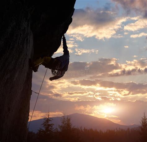 Male Rock Climber Hanging With One Hand While Climbing Stock Photo