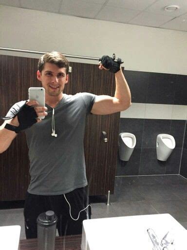 A Man Is Taking A Selfie In The Bathroom With His Cell Phone And Gloves