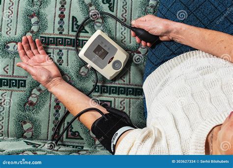 Grandma Takes Her Blood Pressure Sitting On The Couch Stock Photo