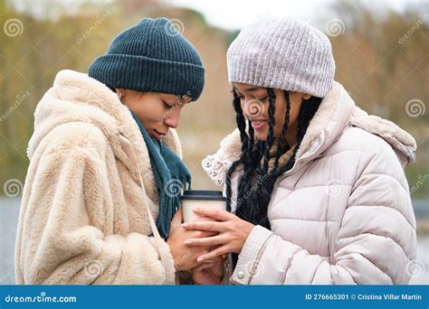 happy dominican lesbian couple with a coffee cup at street in a cold winter day stock image
