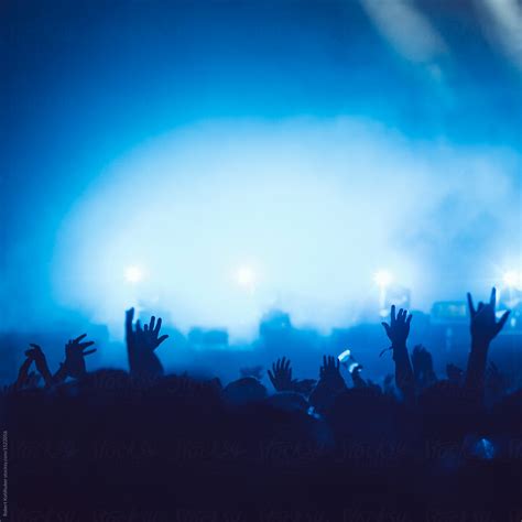 sillhouettes of concert crowd in front of bright stage lights by stocksy contributor robert