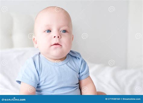 Portrait Of Smiling Baby Boy With Big Blue Eyes In Bodysuit On White