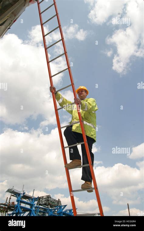 A Construction Worker Climbs An Orange Steel Ladder Photographed From