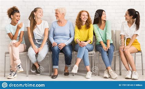 Cheerful Diverse Women Talking Sitting On Chairs Indoor Panorama Stock