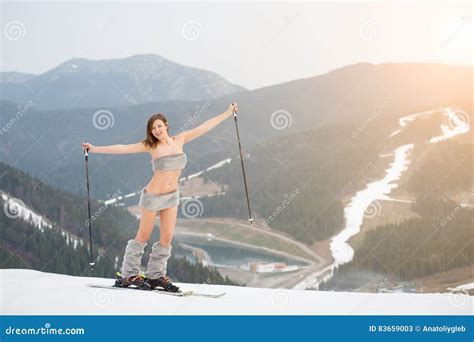 Happy Naked Female Skier Standing On The Snowy Slope Of The Mountain