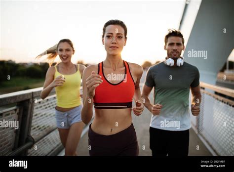 Athletic Fit People Exercising And Running Together Outdoors Stock