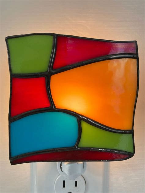 A Multicolored Stained Glass Light Fixture On A White Wall With A