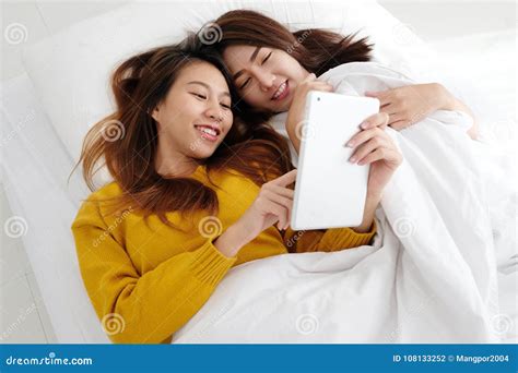 Young Cute Asia Lesbian Couple Using Tablet With Happiness On White Bed