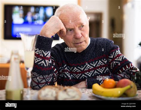 Upset Ederly Man Sitting Alone At Home Table At Christmas Stock Photo