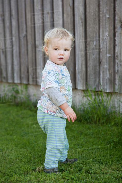 Baby Boy Standing On Grass And Looking Away Stock Photo Dissolve