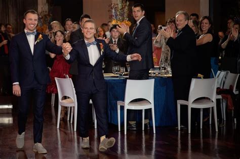 Two Men In Tuxedos Are Dancing At An Event With People Clapping Behind Them