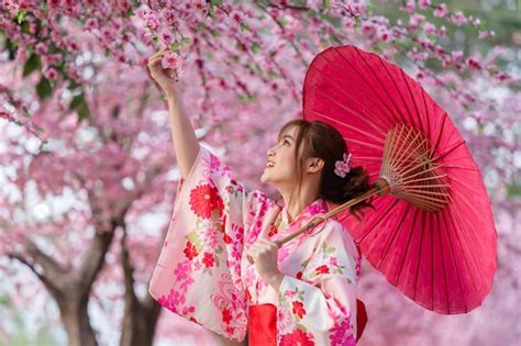 premium photo woman in yukata kimono dress holding umbrella and looking sakura flower or