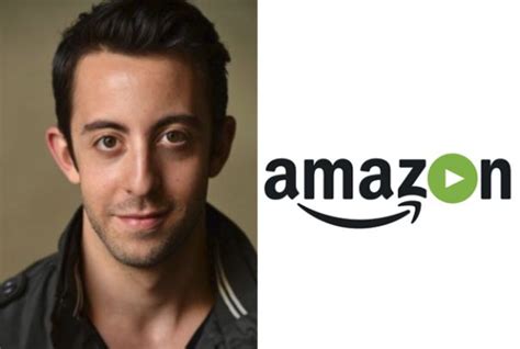 A Man Is Looking At The Camera With An Amazon Logo Behind Him