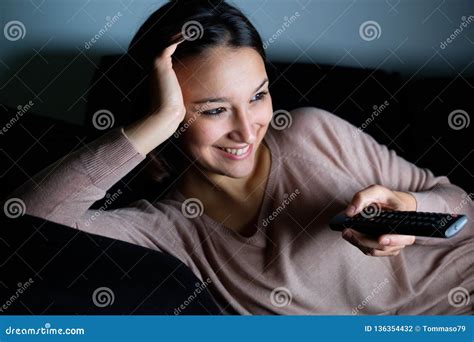 Young Woman Watching Television Alone At Night On The Couch Stock Photo