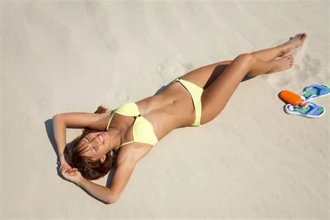 Mujer joven en bikini tomando el sol en la playa fotografía de stock