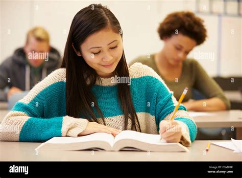 Female High School Student Studying At Desk In Classroom Stock Photo