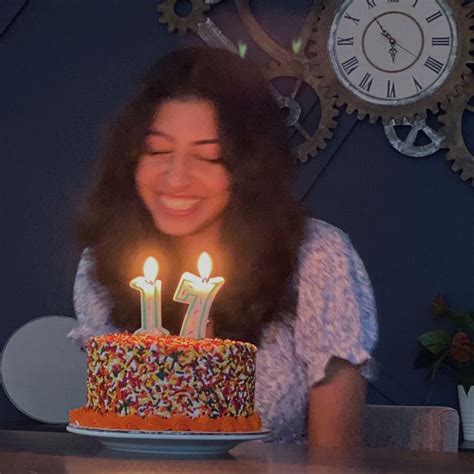 A Woman Sitting In Front Of A Birthday Cake With Two Candles On Top Of It