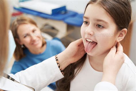 Doctor Examining Child Lymph Nodes And Mouth In Clinic Stock Photo By