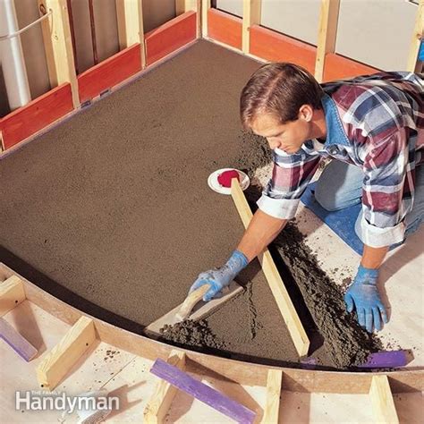 A Man Laying Concrete On Top Of A Floor In A Room With Wooden Framing