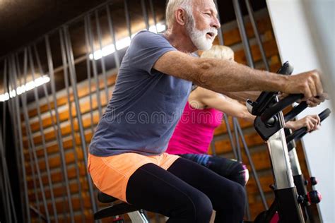 Happy Fit Mature Woman And Man Cycling On Exercise Bikes To Stay Healthy Fotografering F R