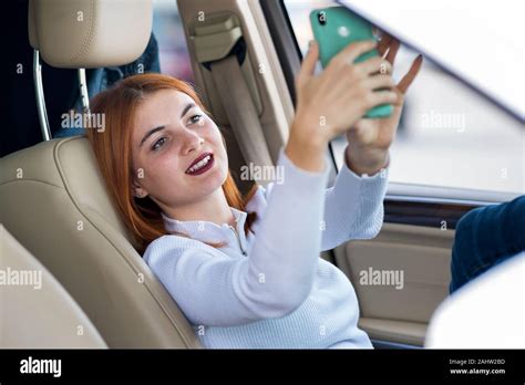Young Redhead Woman Driver Taking Selfies With Her Mobile Phone Sitting
