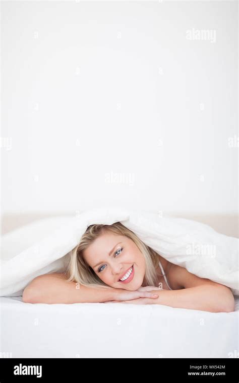 Blonde Woman Lying Under A Duvet In A Bedroom Stock Photo Alamy