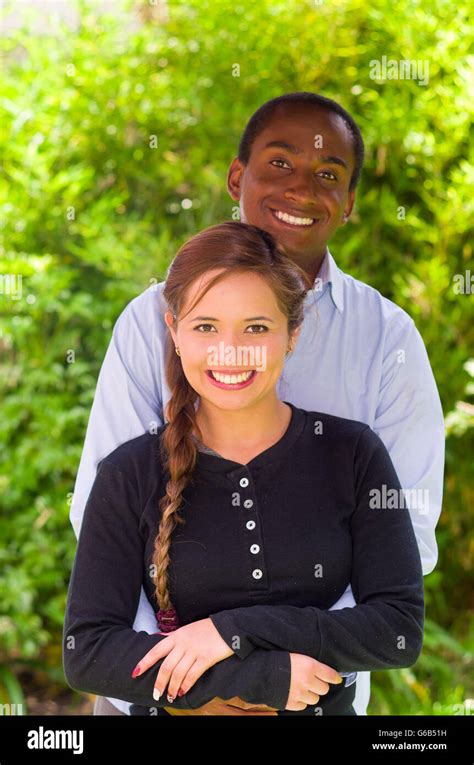 Beautiful Young Interracial Couple In Garden Environment Embracing And