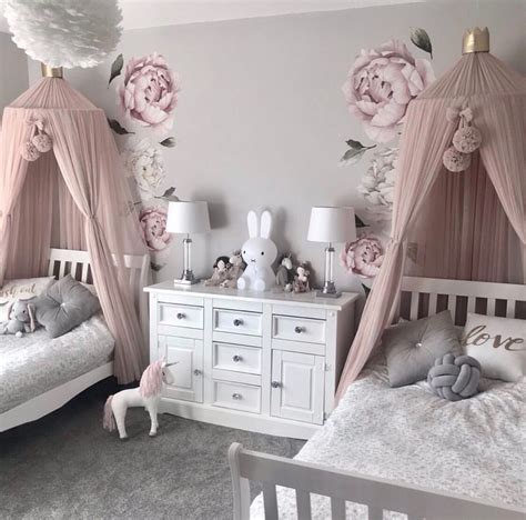 Two White Beds Sitting Next To Each Other In A Room With Pink Flowers On The Wall