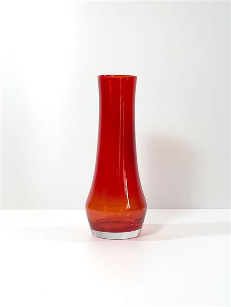 A Red Vase Sitting On Top Of A White Table