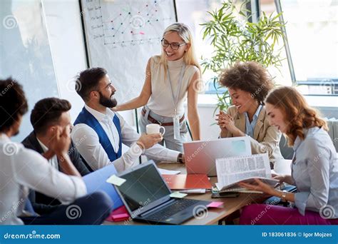 Boss Smiling At Employees Coworkers Chatting In The Office Stock Photo
