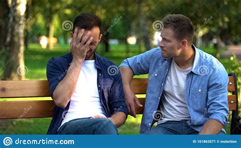 Man Comforting Sad Male Friend Sitting On Bench In Park Life Problems