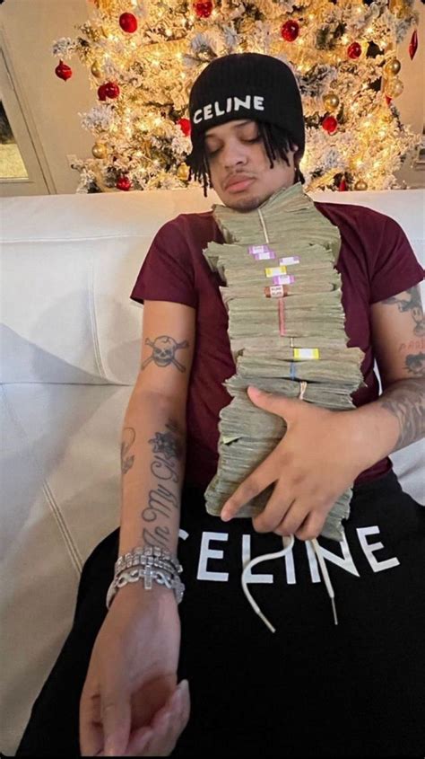 A Man Sitting On Top Of A White Couch Holding Money Wrapped Around His
