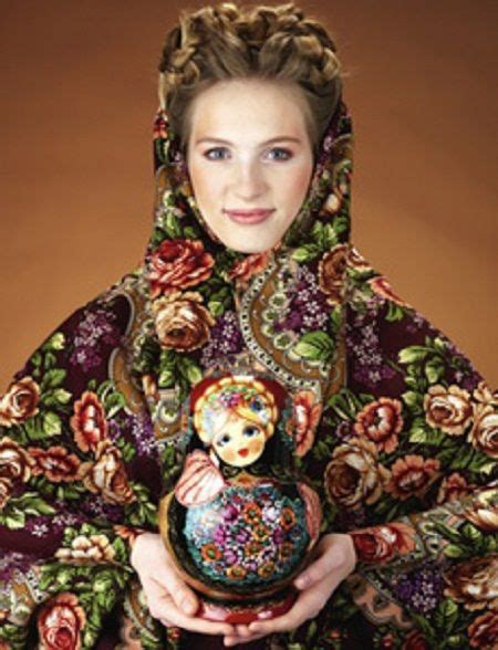 a girl is dressed in russian pavlovsky posad shawl and she is holding a matryoshka doll in her