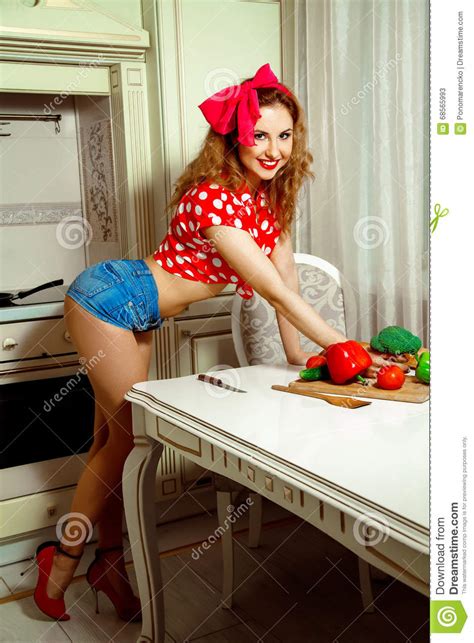 Pin Up Style Housewife Posing In The Kitchen And Smiling