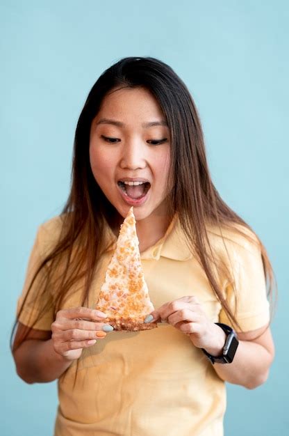 Free Photo Brunette Asian Woman Eating A Slice Of Pizza