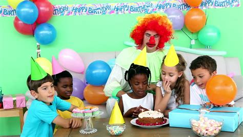 Seven Little Kids Sit At Red Table With Cake And Throw Confetti At