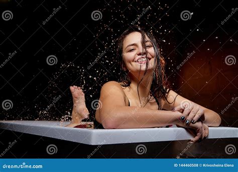 Young Pretty Brunette Woman In Bath With Water And Splashes And Drops