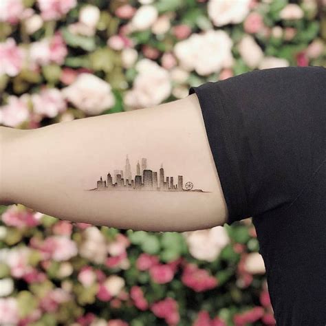 A Womans Arm With A City Skyline Tattoo On The Left Side Of Her Arm