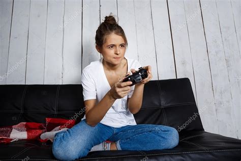 Beautiful Girl Playing Video Games Sitting On Sofa At
