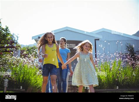 Happy Sisters With Parents Walking Behind Against House Stock Photo Alamy