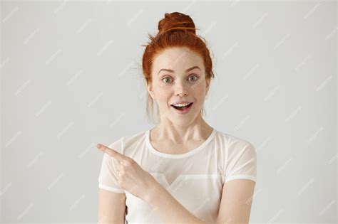 Free Photo Excited Young Redhead Caucasian Woman With Hair Knot Pointing Her Index Finger