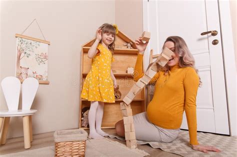 Een Zwangere Vrouw Speelt In De Kinderkamer Met Haar Dochter Stock Foto Image Of Familie