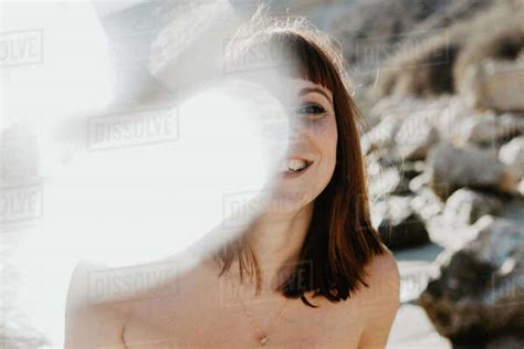 Spots Of Bright Sunlight In Front Of Naked Female Looking At Camera Against Cloudless Sky In