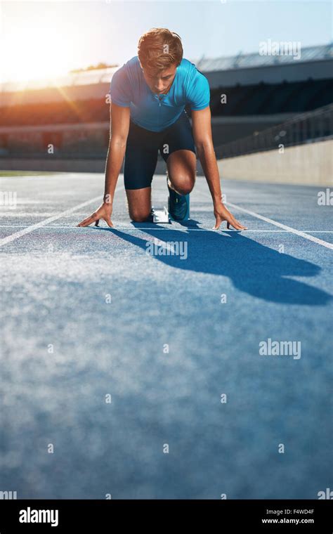 Professional Male Track Athlete In Set Position On Sprinting Blocks Of