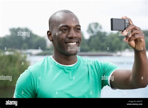 Smiling Man Taking Photograph Of Himself By Lake Stock Photo Alamy